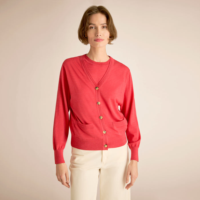 Woman wearing a red cardigan with gold buttons on a beige background