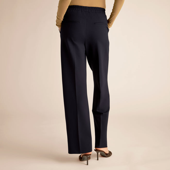 Navy blue pants worn by a person on a beige background