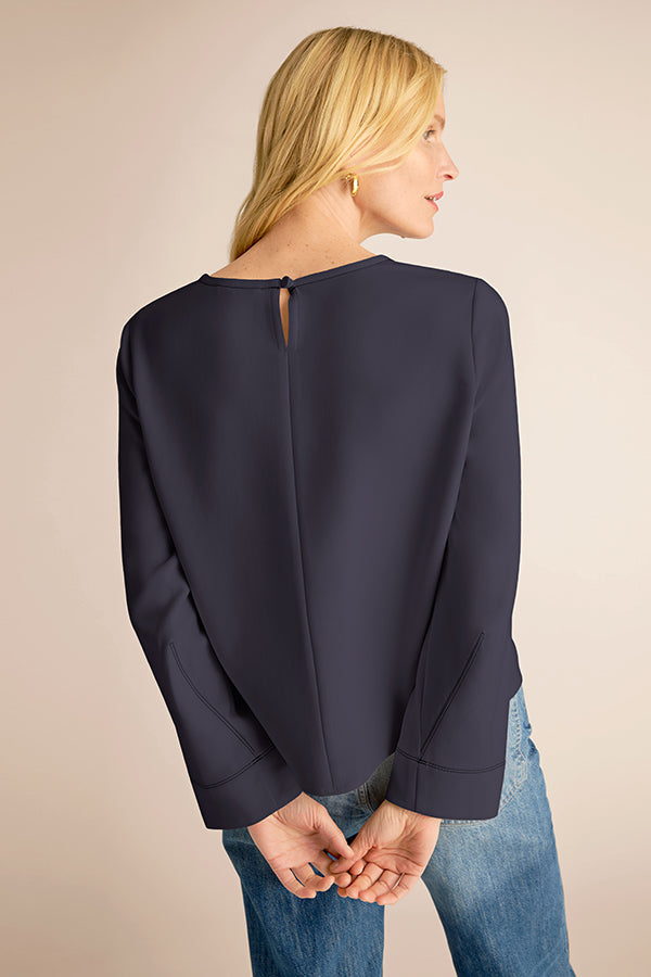Woman wearing a navy blue blouse with a beige background | Exclude | Grid Hover