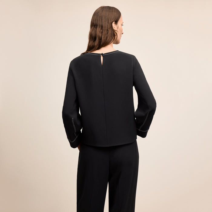Woman wearing a black outfit on a beige background