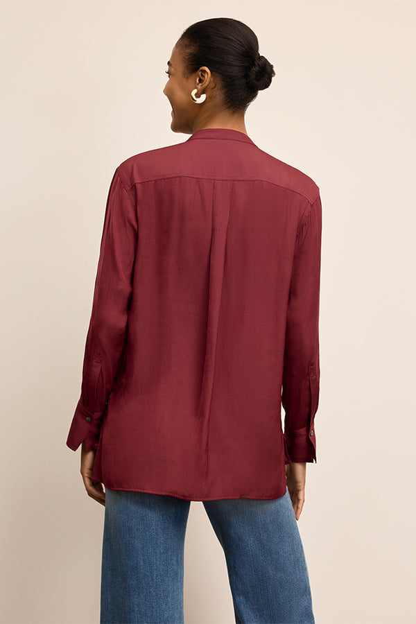 Person wearing a burgundy shirt and blue jeans on a beige background | Exclude
