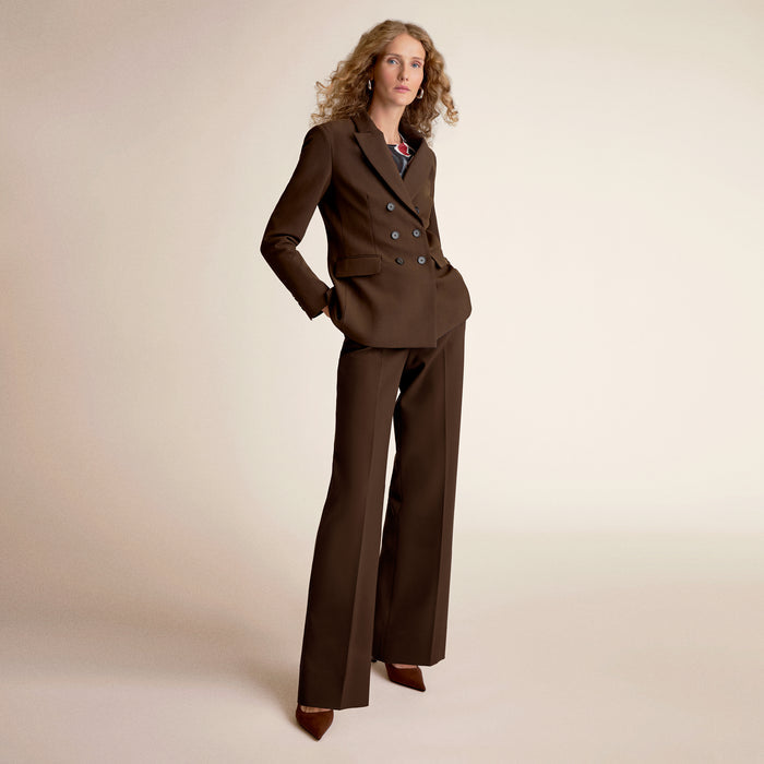 Woman wearing a brown suit against a beige background | Lead