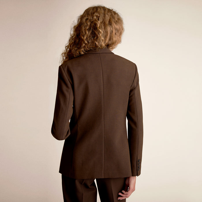 Person wearing a brown suit jacket on a beige background