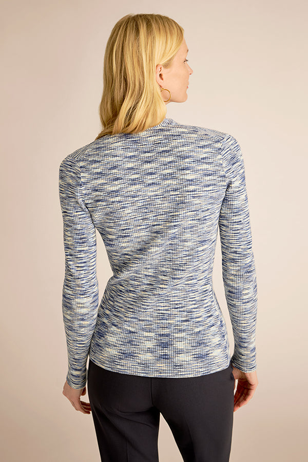 Person wearing a blue and gray patterned long-sleeve top on a beige background | Exclude