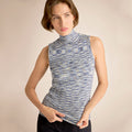 Woman wearing a sleeveless patterned top against a beige background | Lead