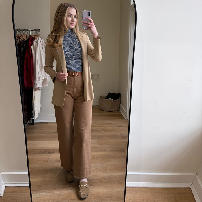 Person taking a mirror selfie wearing a beige suit in a room with a large floor mirror.