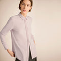 Woman wearing a light purple shirt against a beige background | Lead