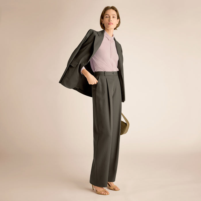 Woman wearing a gray suit with a pink top on a beige background