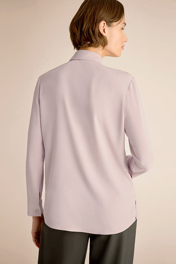 Light purple blouse worn by a person on a beige background | Exclude | Grid Hover