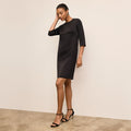 Woman wearing a black dress against a plain background | Lead