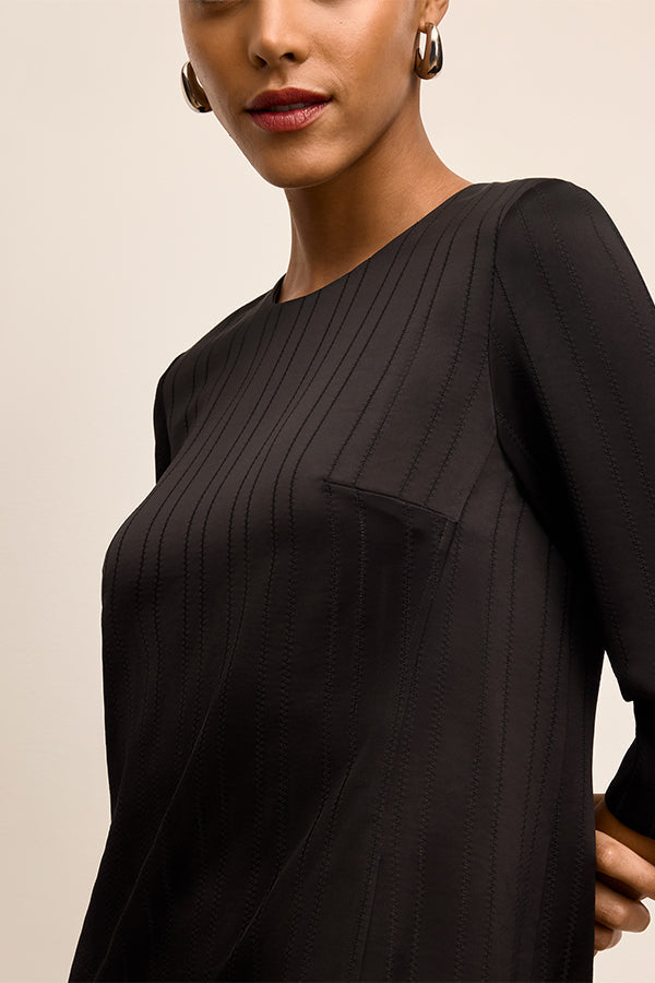 Woman wearing a black dress with long sleeves on a beige background | Exclude | Grid Hover