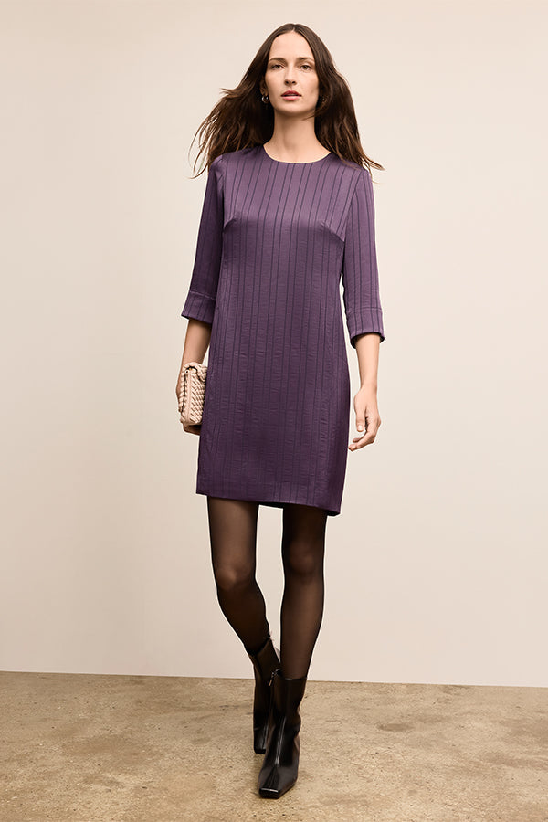 Woman wearing a purple dress against a beige background | Exclude | Grid