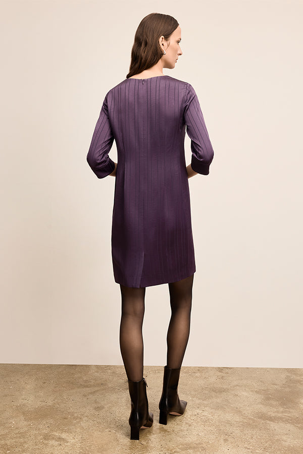 Woman wearing a purple dress standing against a plain background | Exclude | Grid Hover
