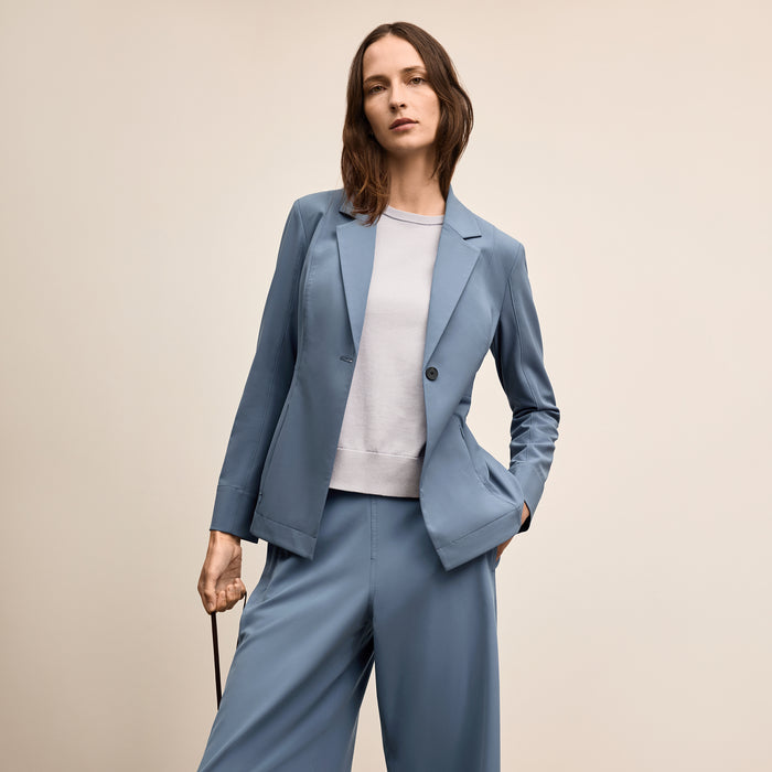 Woman wearing a blue suit with a white shirt on a beige background