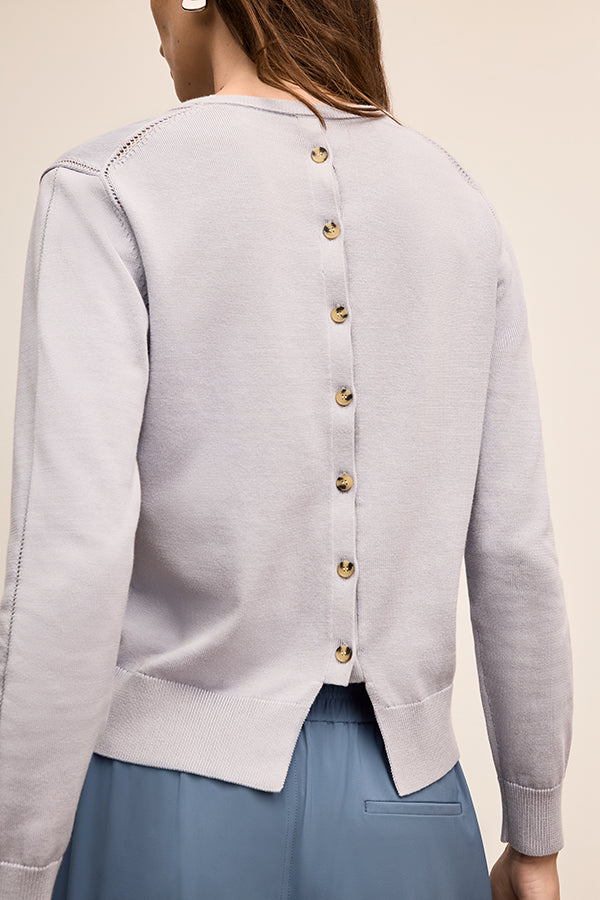 Light gray cardigan with gold buttons worn by a person on a beige background | Exclude | Grid Hover