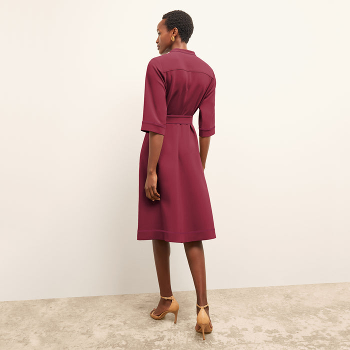 Woman wearing a burgundy dress standing against a plain background