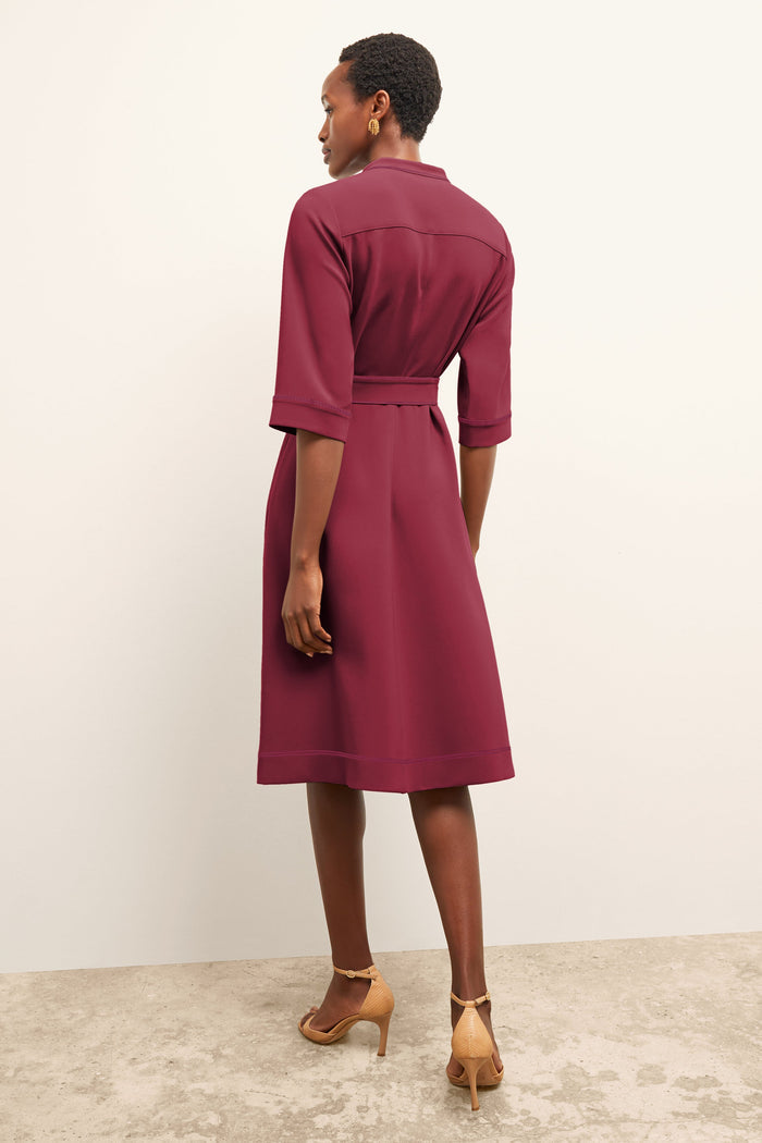 Woman wearing a burgundy dress standing against a plain background | Grid Hover | Exclude