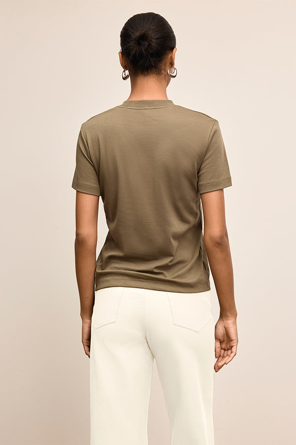Person wearing a brown t-shirt and white pants on a beige background  | Exclude | Grid Hover