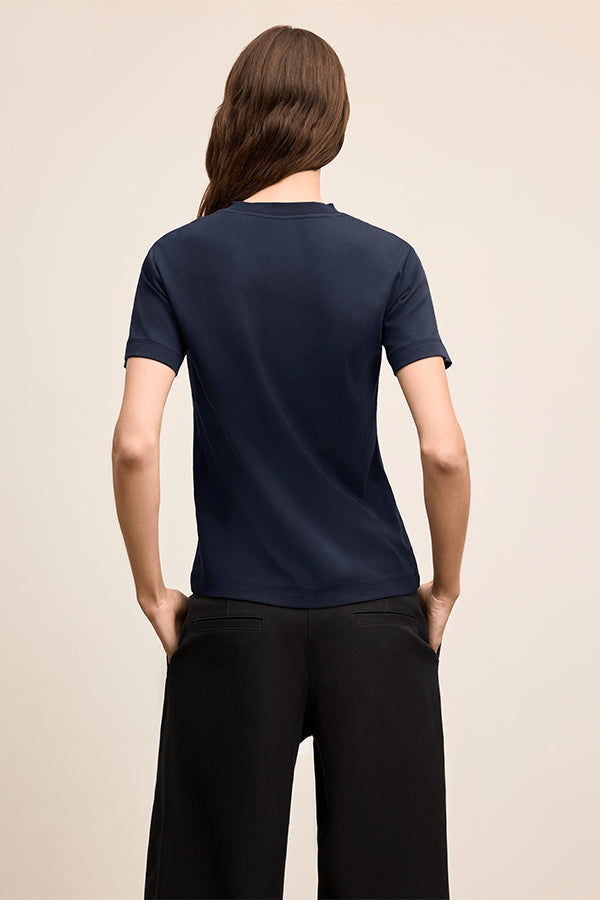 Person wearing a navy blue t-shirt and black pants on a beige background | Exclude