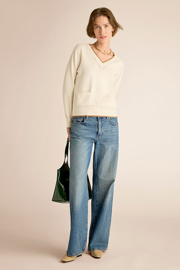Woman wearing a cream sweater and blue jeans against a beige background | Exclude | Grid
