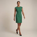 Woman wearing a green dress against a beige background | Lead