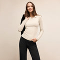 Woman wearing a beige sweater and black pants against a plain background  Lead