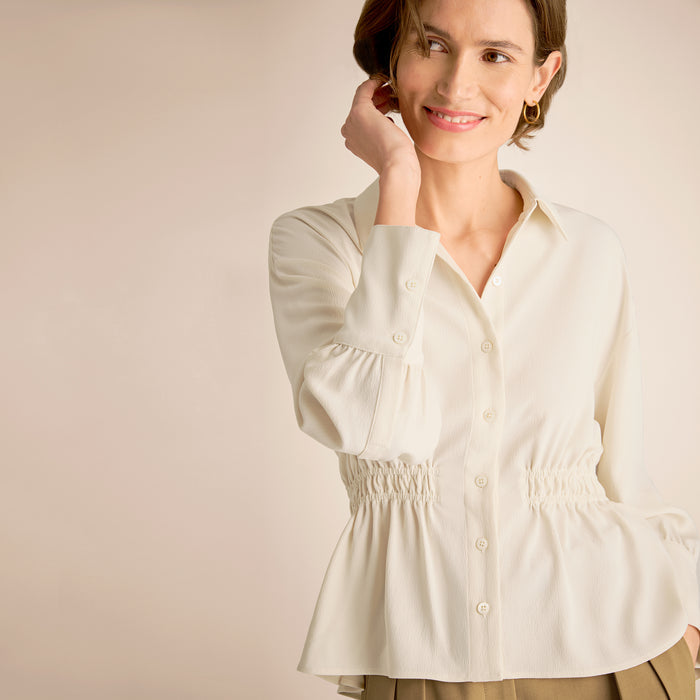 Woman wearing a white blouse against a beige background | Lead