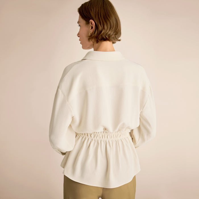 Woman wearing a white blouse against a beige background