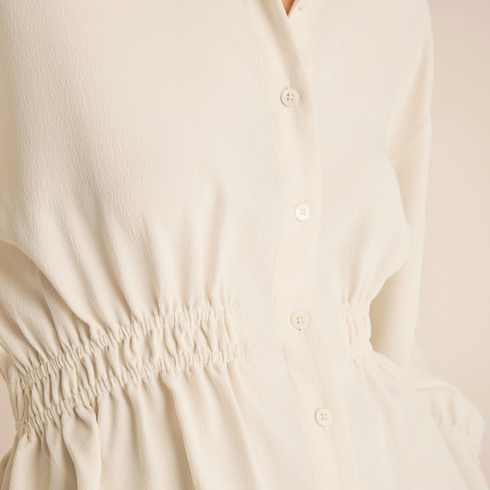 Close-up of a beige dress with button details on a light background