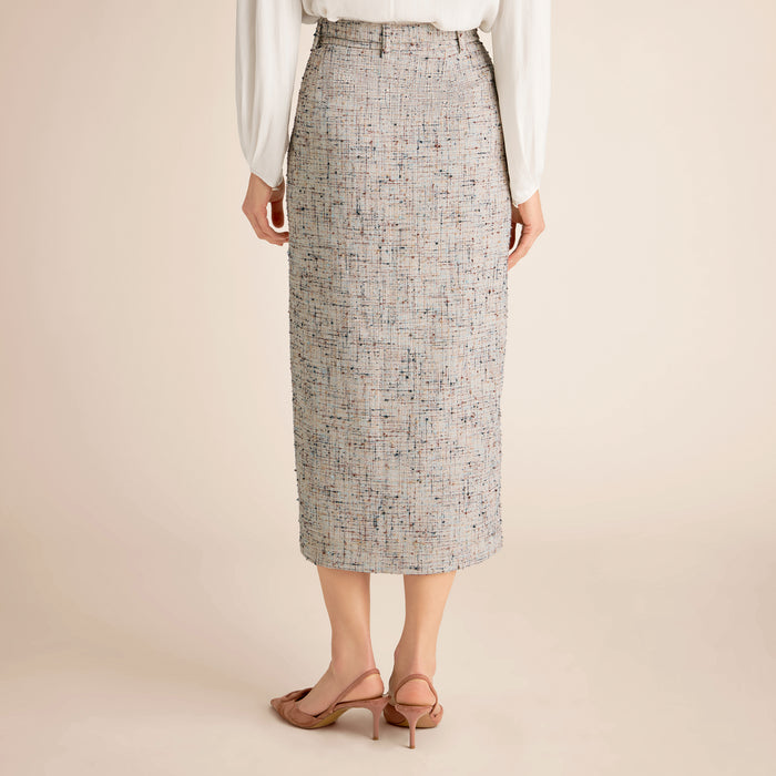 Person wearing a patterned skirt on a beige background