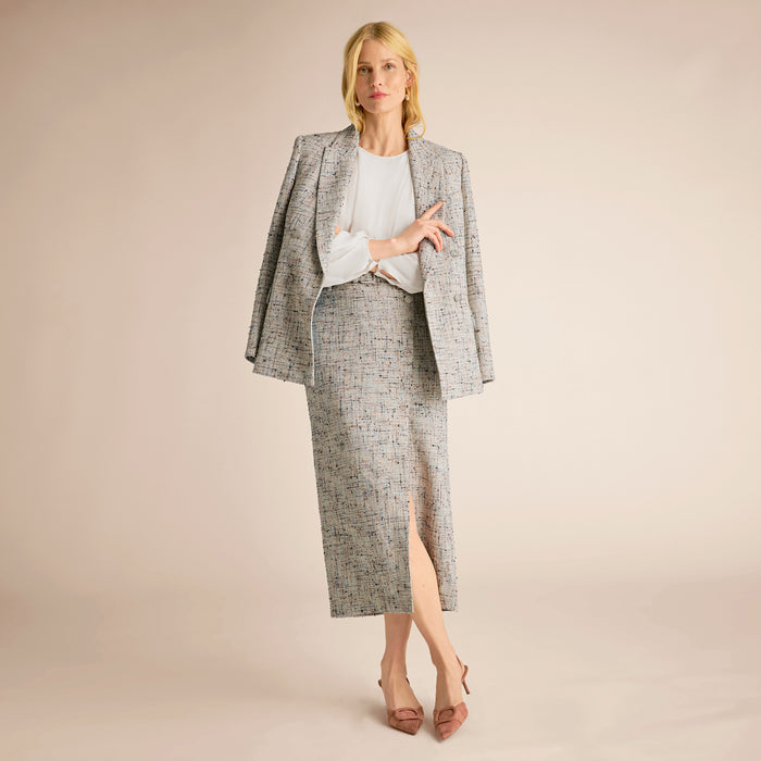 Woman wearing a gray patterned suit on a beige background