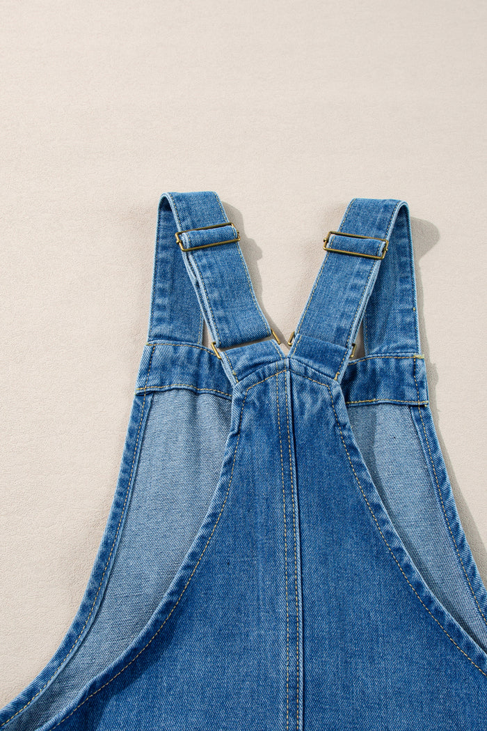 Mini-robe en jean bleu crépuscule à larges bretelles boutonnées avec poches sur le devant