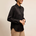 Woman wearing a black blouse against a beige background | Lead