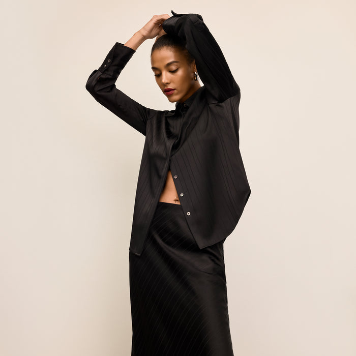 Woman wearing a black outfit against a beige background