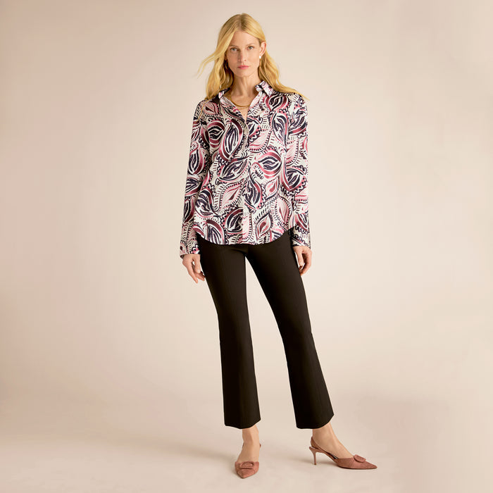 Woman wearing a patterned blouse and black pants on a beige background