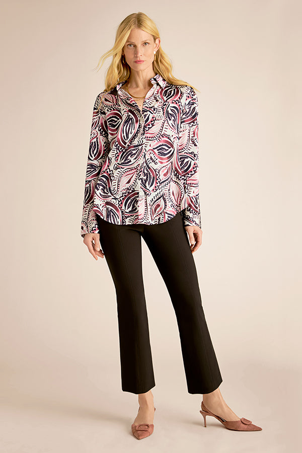 Woman wearing a patterned blouse and black pants on a beige background | Grid Hover | Exclude