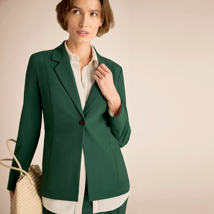 Woman wearing a green blazer over a white shirt on a beige background | Lead