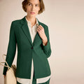 Woman wearing a green blazer over a white shirt on a beige background | Lead
