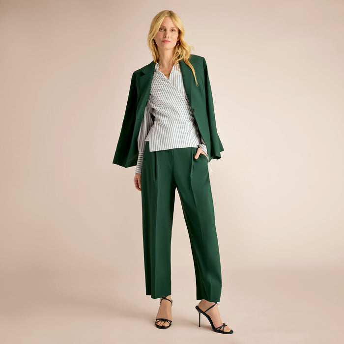 Woman wearing a green suit with a white shirt on a beige background