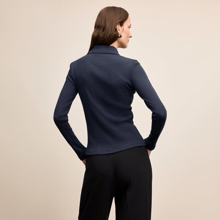 Woman wearing a navy blue long-sleeve top on a beige background