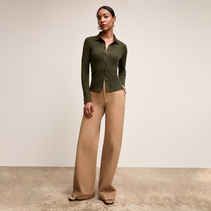 Woman wearing a green cardigan and beige pants against a neutral background | Lead