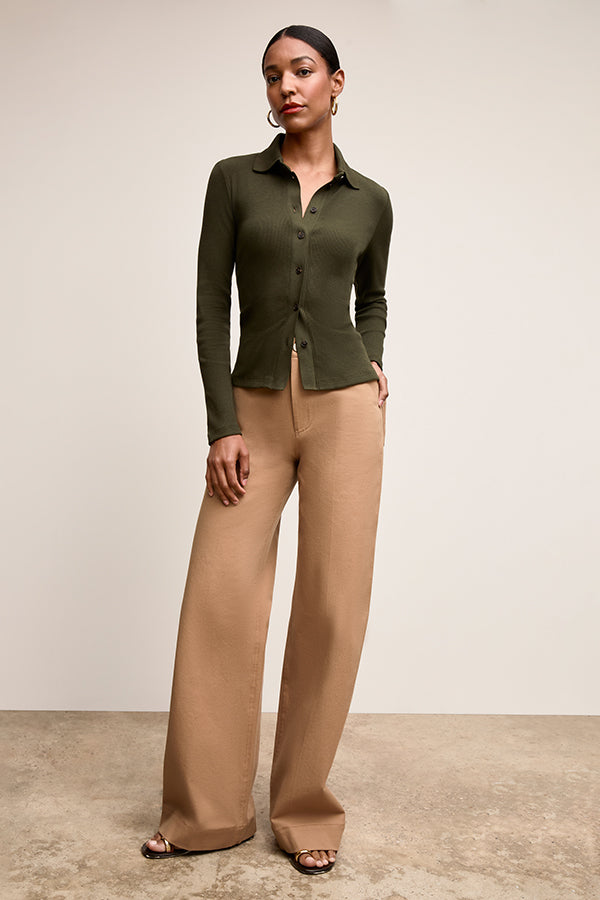 Woman wearing a green cardigan and beige pants against a neutral background | Exclude | Grid