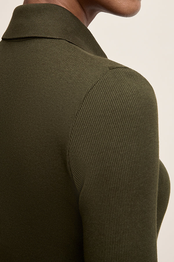 Close-up of a person wearing a ribbed green sweater against a neutral background | Exclude