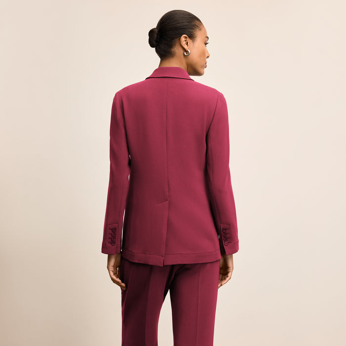 Person wearing a burgundy suit on a beige background