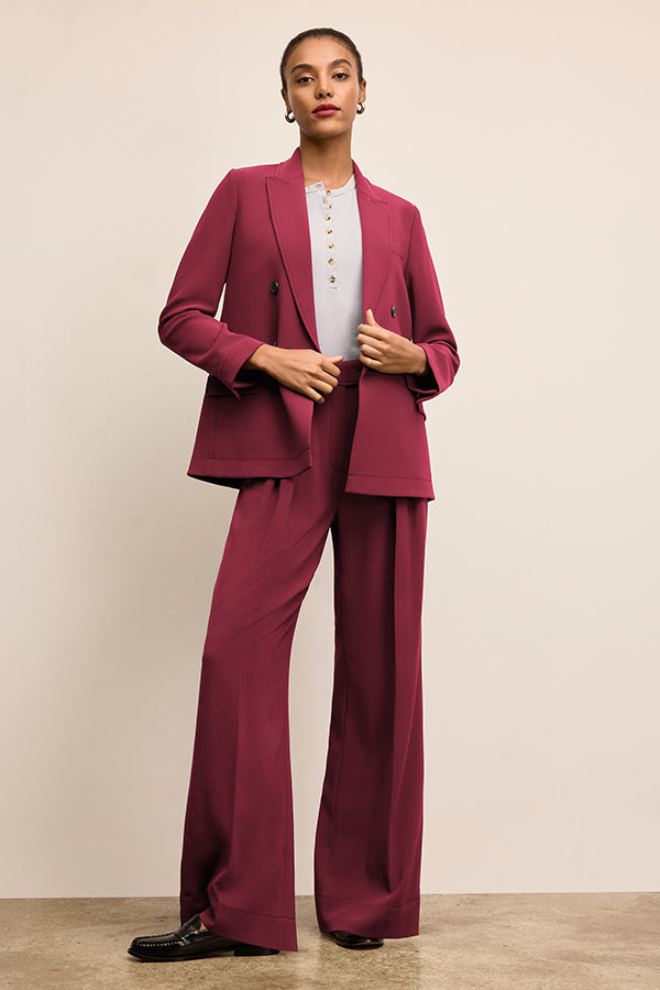 Woman wearing a burgundy suit with a white shirt against a beige background | Grid | Exclude