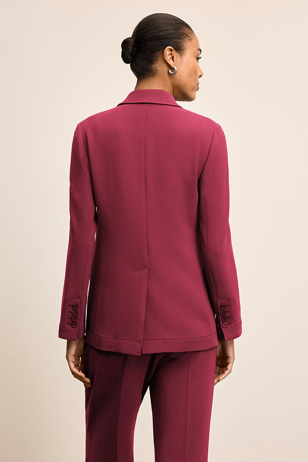 Person wearing a burgundy suit on a beige background | Grid Hover | Exclude