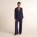 Woman wearing a navy and white knit tank top with navy pleated trouser pants and matching blazer | Lead