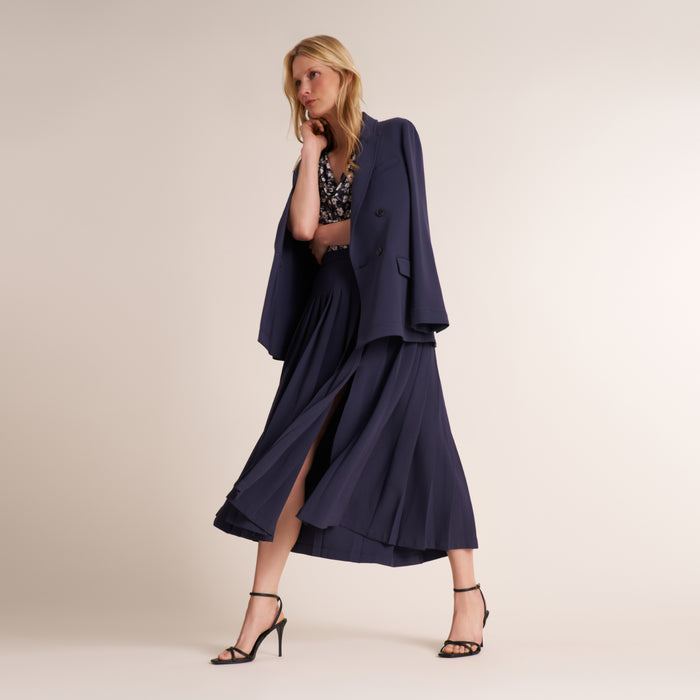 Woman wearing a double breasted blazer over a matching pleated skirt