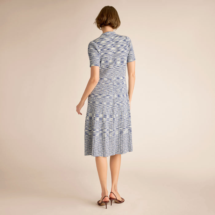 Woman wearing a blue patterned dress on a beige background