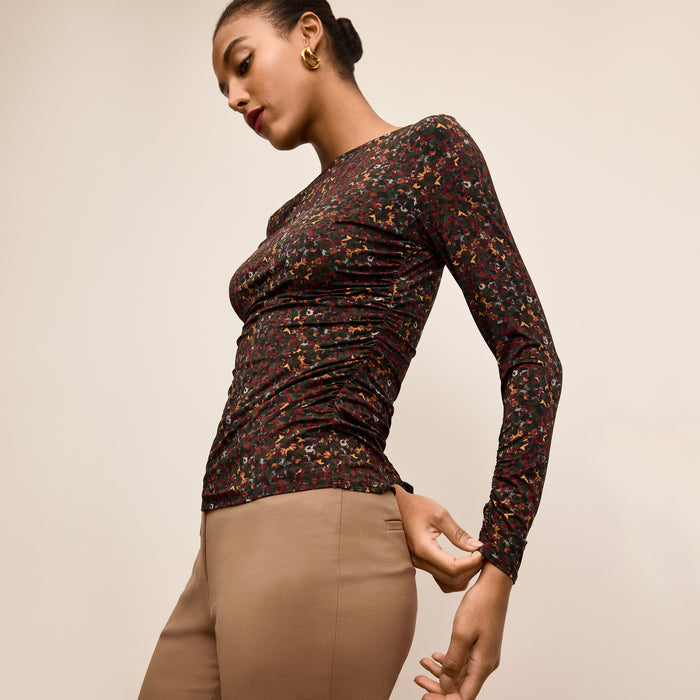 Woman wearing a patterned long-sleeve top and beige pants on a beige background | Lead